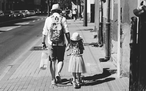Man Holding Girl While Walking on Street